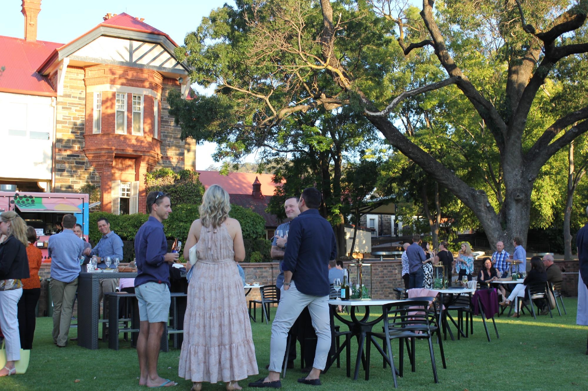 Parents and guests gathered on the Mercedes College lawns for an evening event with the heritage building in the background.